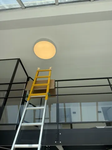 Applique LED ronde posée dans un loft à verrière d'atelier